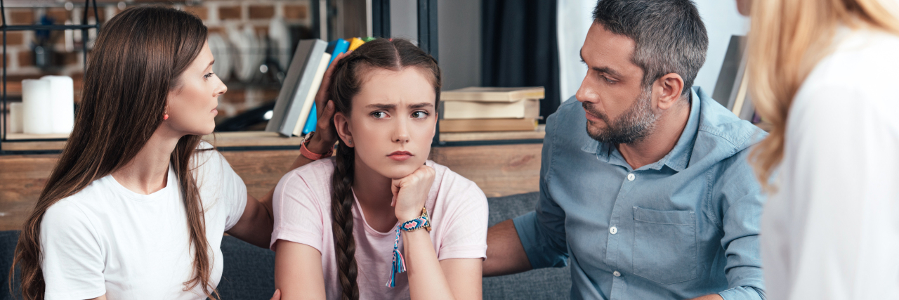 photo of parents with daughter in therapy session sitting on sofa in front of female therapist