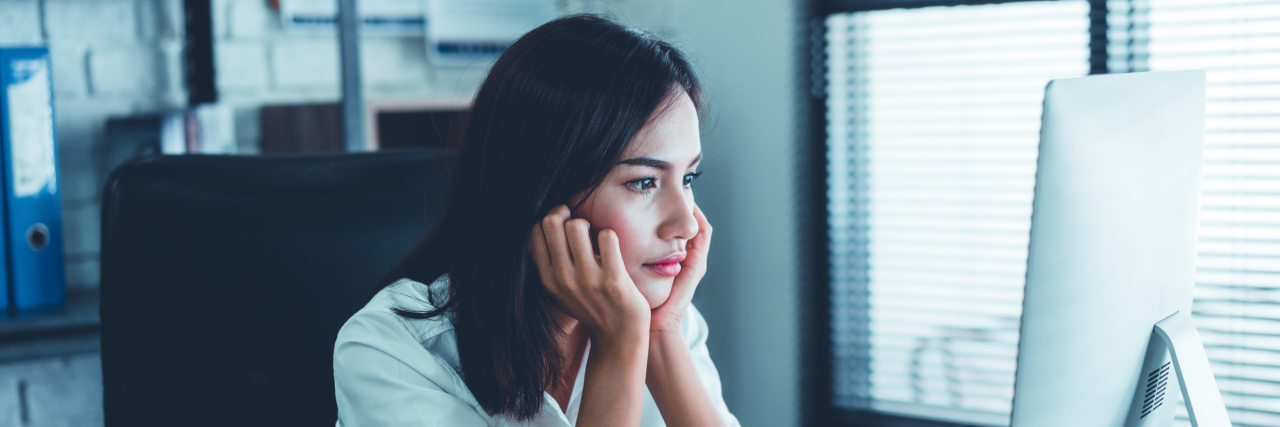 woman looking tiredly at a computer