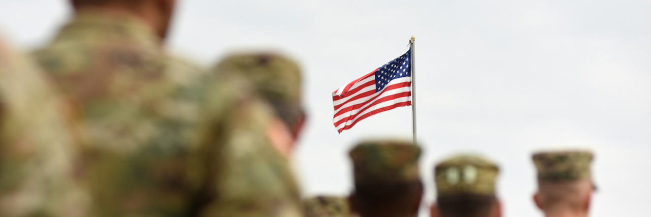 American Soldiers in a line in front of an American Flag