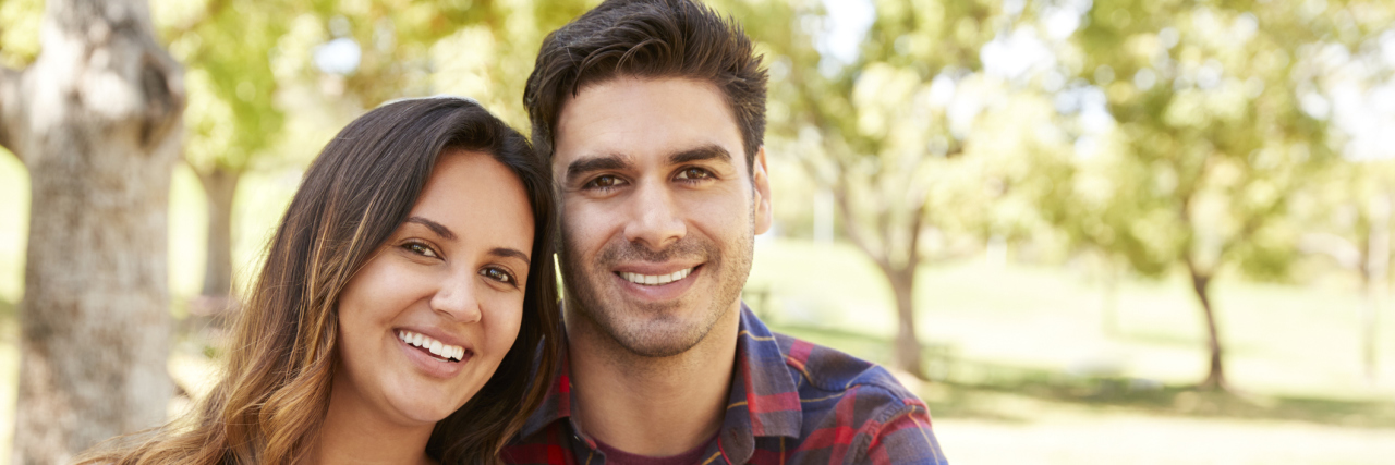 Cómo Tener Una Hija Con Discapacidades Ha Impactado Nuestro Matrimonio Pareja sentada en una mesa de picnic sonriendo a la cámara