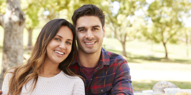 Pareja sentada en una mesa de picnic sonriendo a la cámara