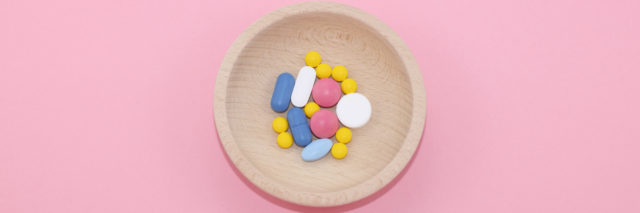 Different kinds of pharmaceutical tablets on pink paper background.