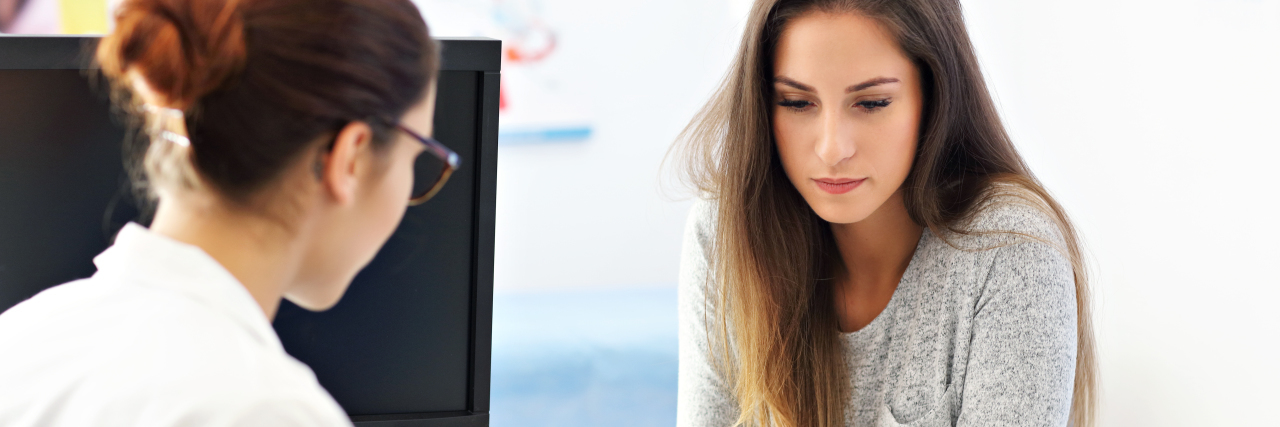 photo of woman talking to female doctor in office