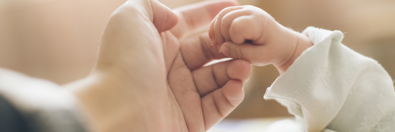 Don't Compare Parenting a Child With Complex Medical Needs close up photo of father's hand and baby's hand in his