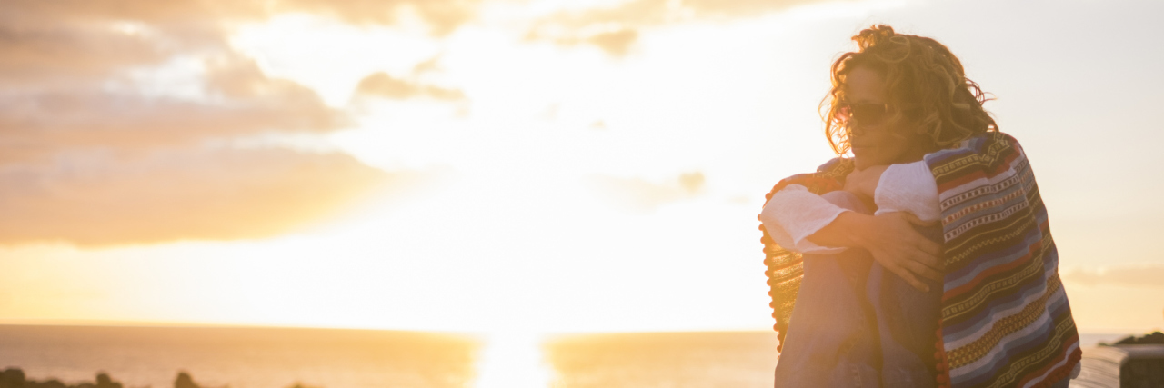 10 Mental Health Challenges Cancer Survivors Go Through Beautiful curly woman sitting on a wall and enjoy the sunset time feeling the freedom sensation on her skin and feed with nice thoughts her mind