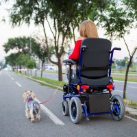 Woman in power wheelchair walking her dog.