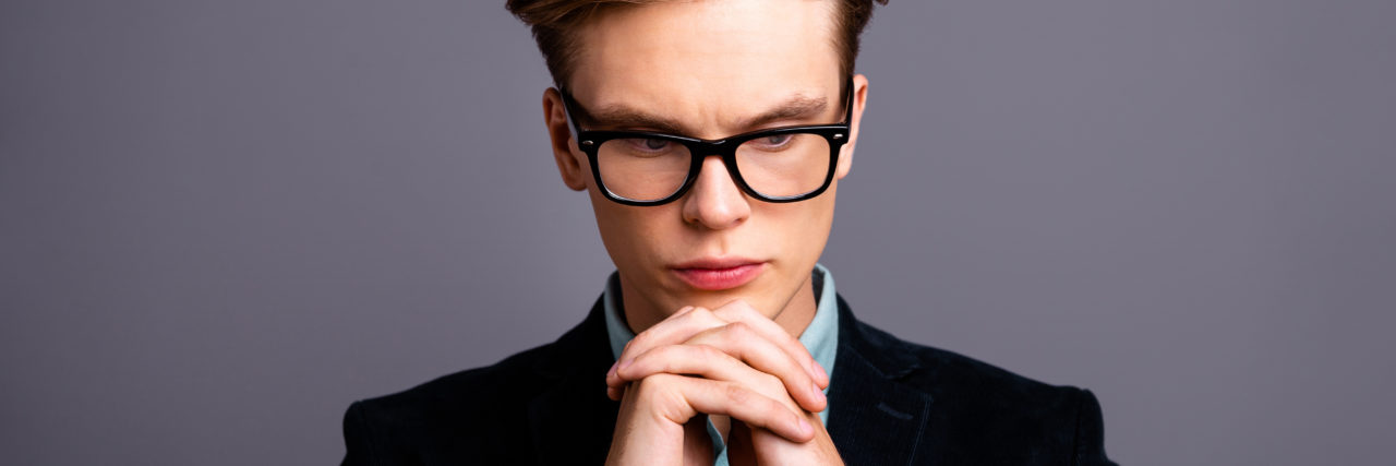 blond man with glasses looking down