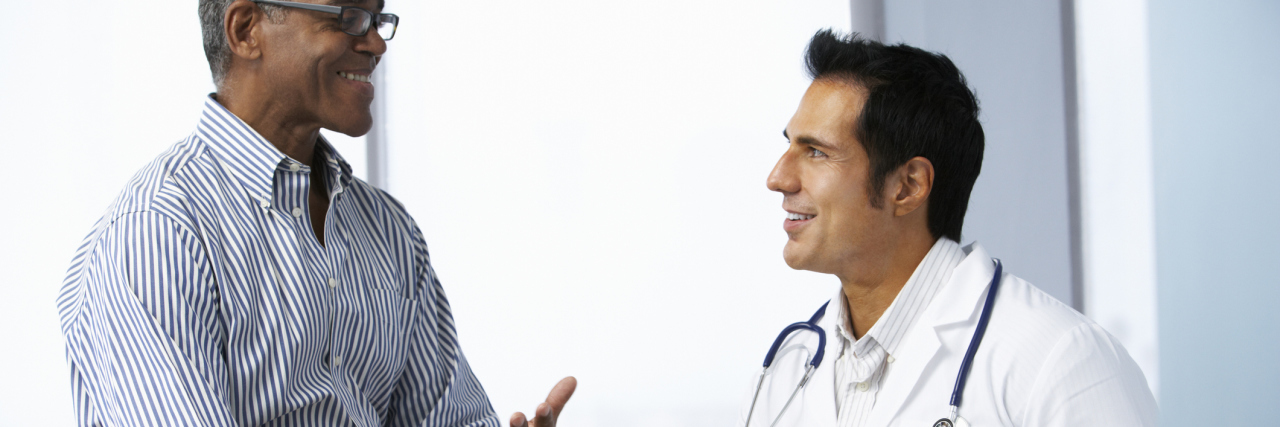 What It Was Like Treating My Prostate Cancer With HIFU Doctor In Surgery With Male Patient Using Digital Tablet Smiling To Each Other.