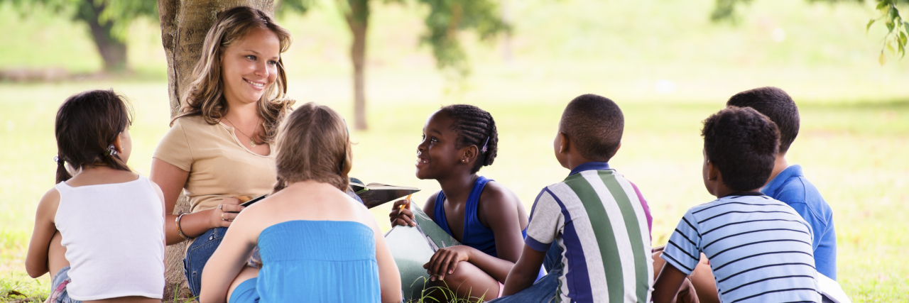 Being Called 'Amazing' for Living Life With a Disability Camp counselor sitting under tree with campers.