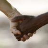 White and black person holding hands.