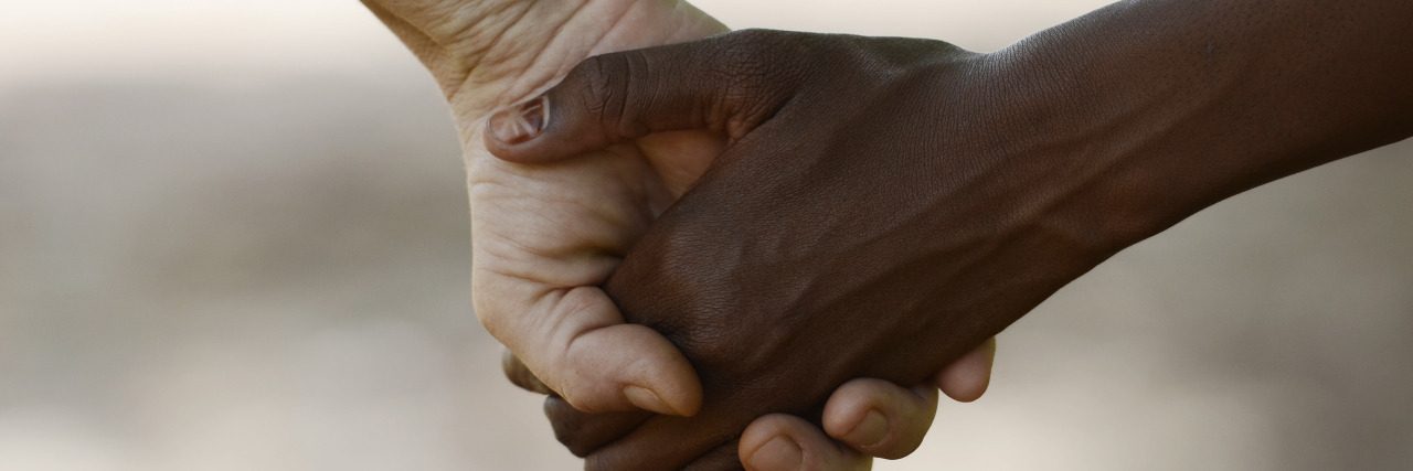 White and black person holding hands.