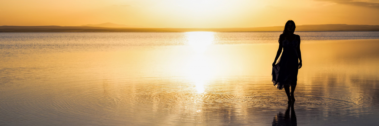 Developing Body Positivity With Lupus Silhouette of a woman on the beach at sunset.