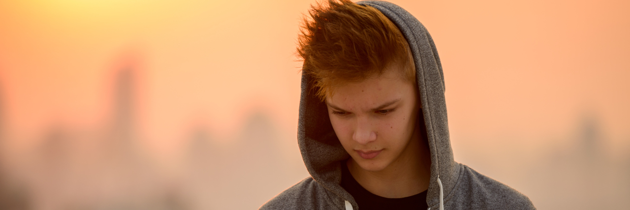 A Parent’s Guide to Battling Teen Suicide a teenage boy looking a his phone