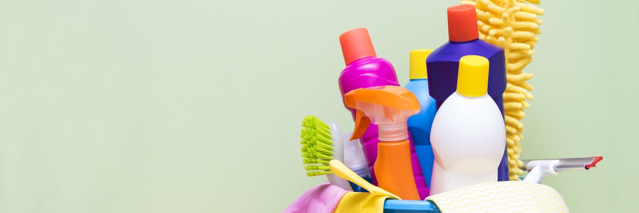 Hiring a Cleaning Helper as Someone With a Chronic Illness House cleaning products on wood table with green background.