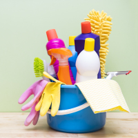 House cleaning products on wood table with green background.