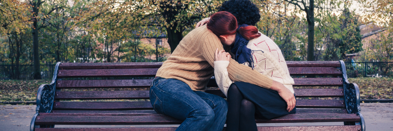 How to Support a Loved One With Mental Illness A couple is embracing while sitting on a park bench