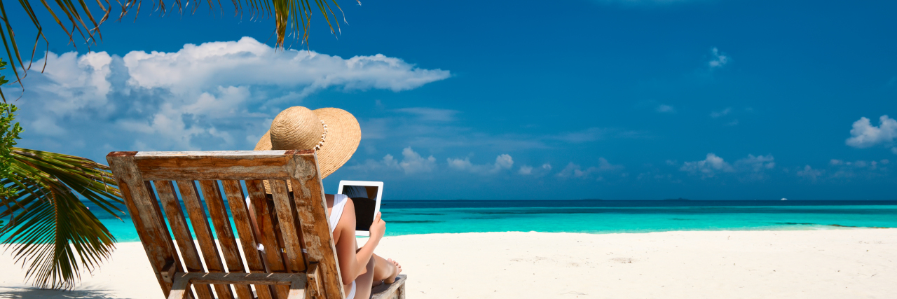 E-Readers Make Reading Accessible for People With Disabilities Young woman with e-reader on the beach.