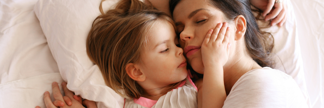 mother and daughter sleeping in bed