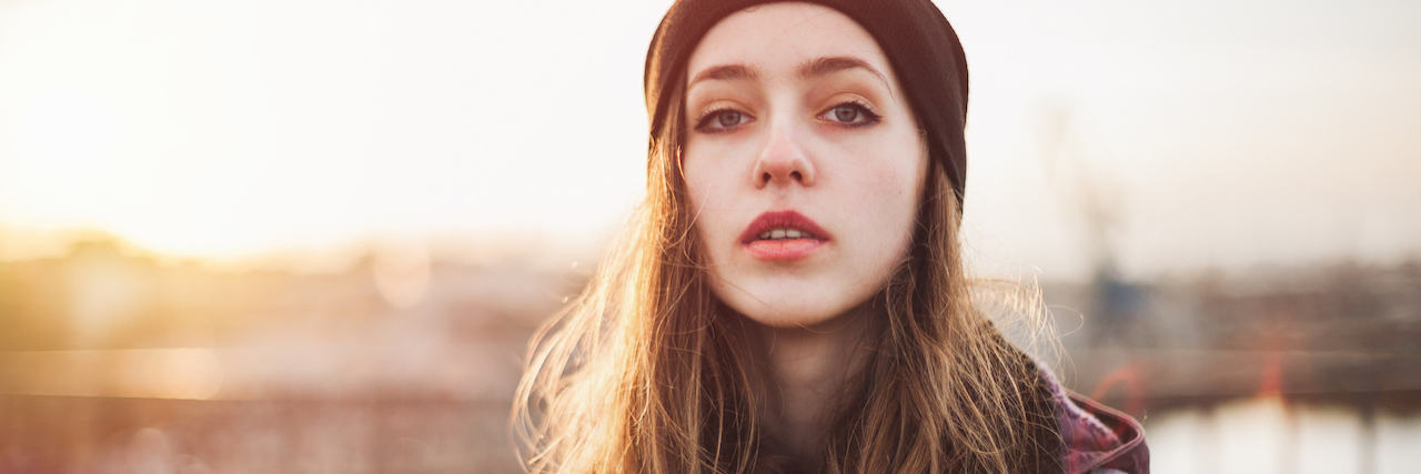 A young woman wearing a beanie at dusk