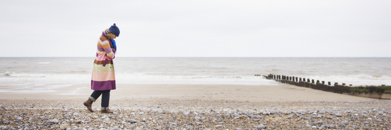 I am Alive, but I'm Not Living a woman is walking on the beach