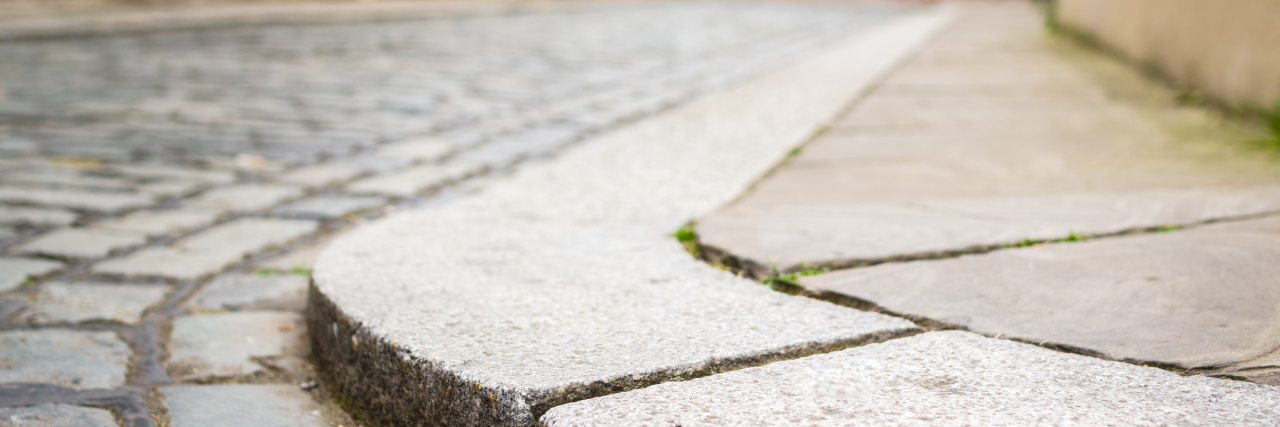 Listen to Disabled People When We Talk About Accessibility Curb on cobbled street