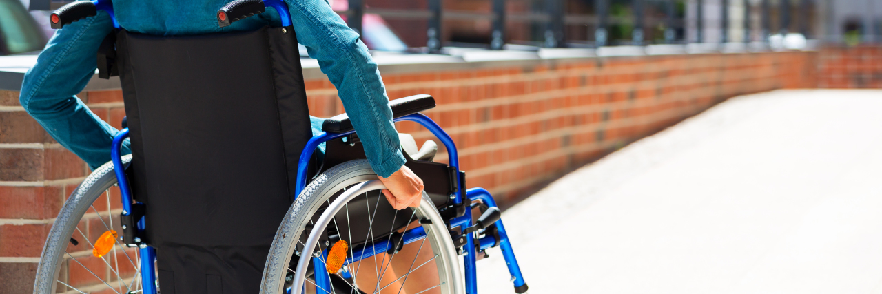What to Know About Living With Osteogenesis Imperfecta woman in a wheelchair on the pavement