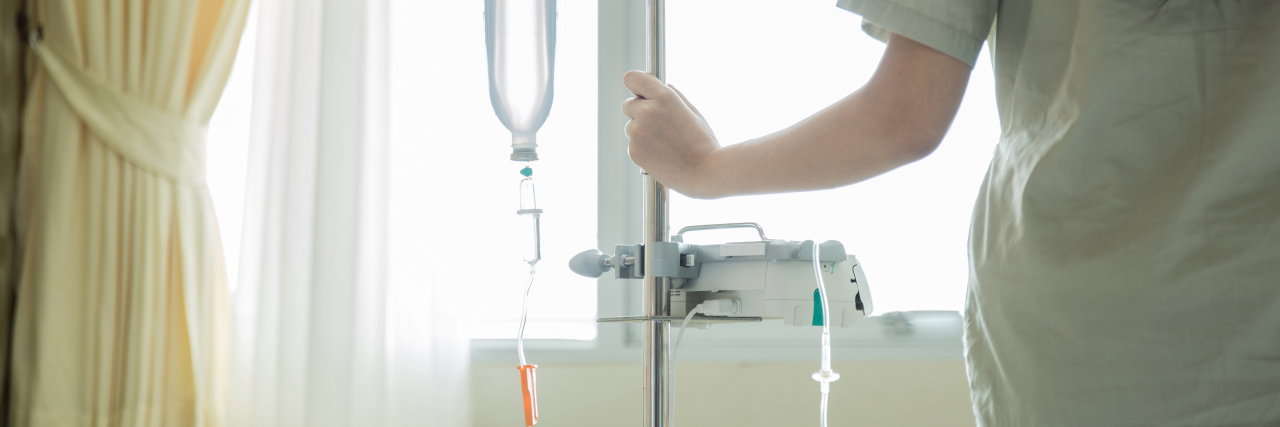 Finding Predictability and Friendship in Hospital With Chronic Illness photo of woman standing at window holding IV drip pole