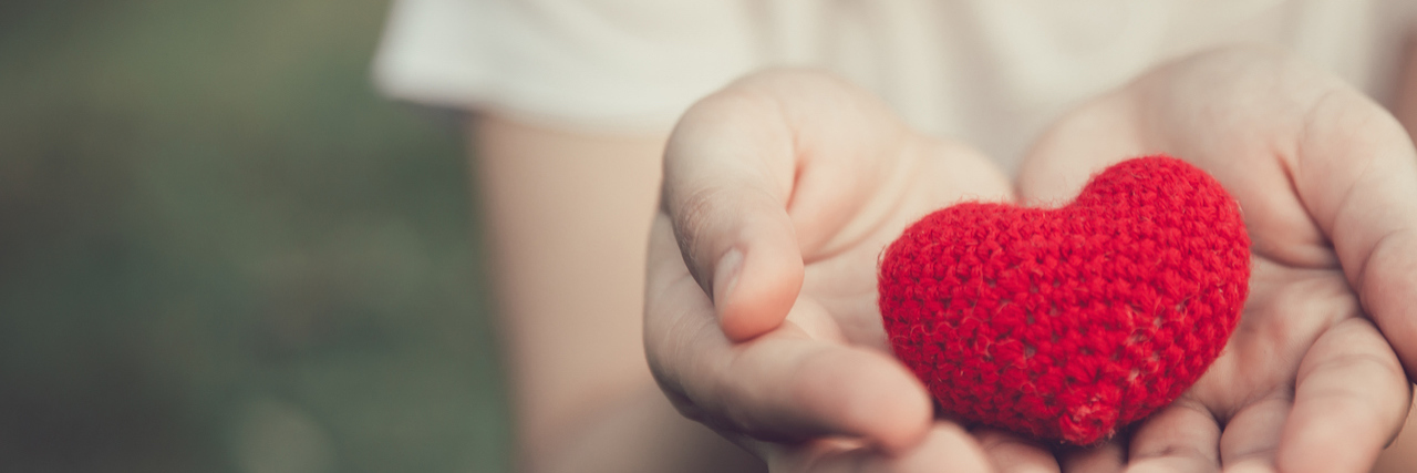 A woman holding a knitted heart