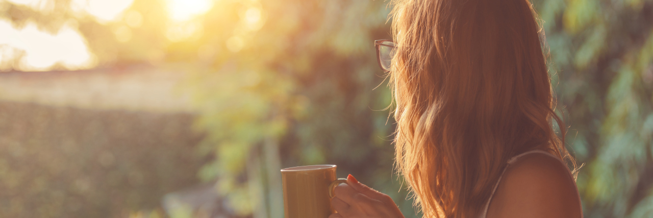What Alcohol Recovery Looks Like in Motherhood A young woman drinking coffee on a porch.