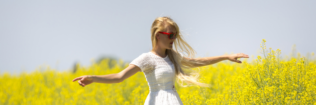 Why Stimming Is Essential for People With Autism Woman spinning joyfully in a field of flowers.