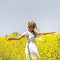 Woman spinning joyfully in a field of flowers.