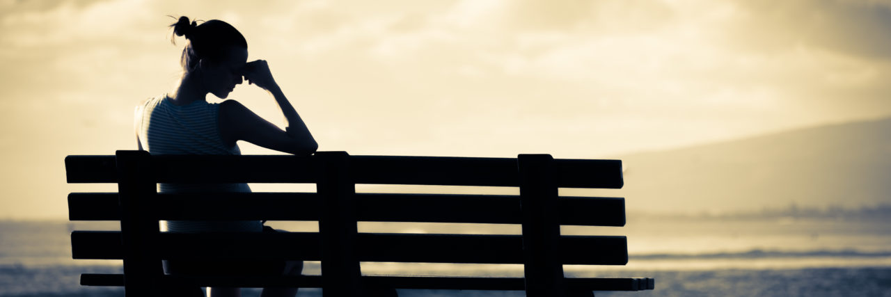 Living With Multiple Chronic Illnesses Woman sitting alone on a park bench.