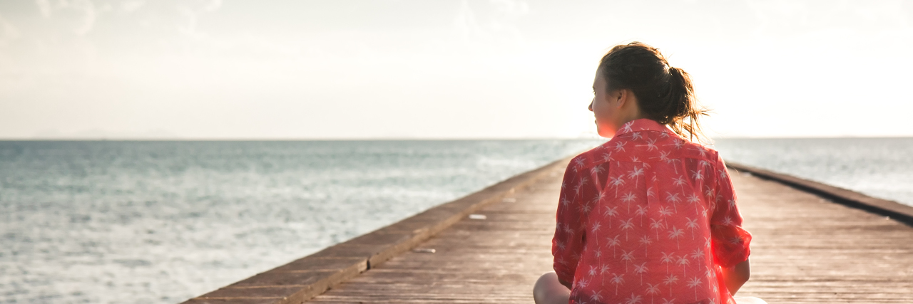 Lessons from Living With Fibromyalgia as a Student young woman sitting on a dock near the water