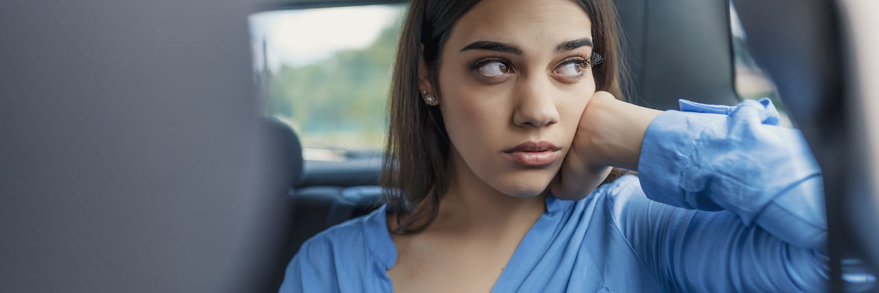 How Childhood Neglect Affects You as an Adult A woman sitting in a car, looking out the window