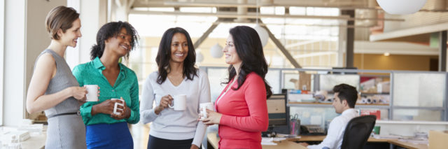 Female work colleagues chatting over coffee in the office