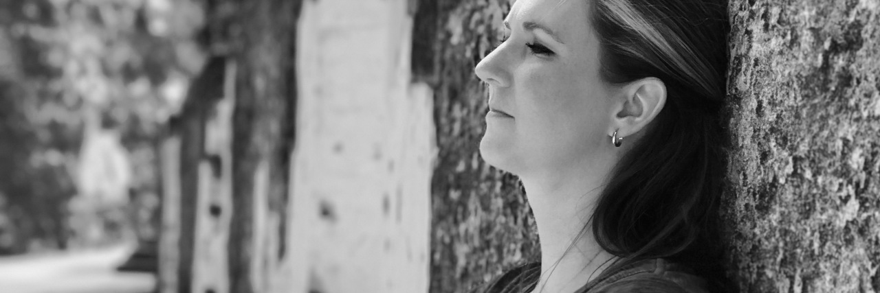 We Need to Believe, Not Invalidate, Fellow Chronic Illness Warriors black and white photo of contributor learning back on wall