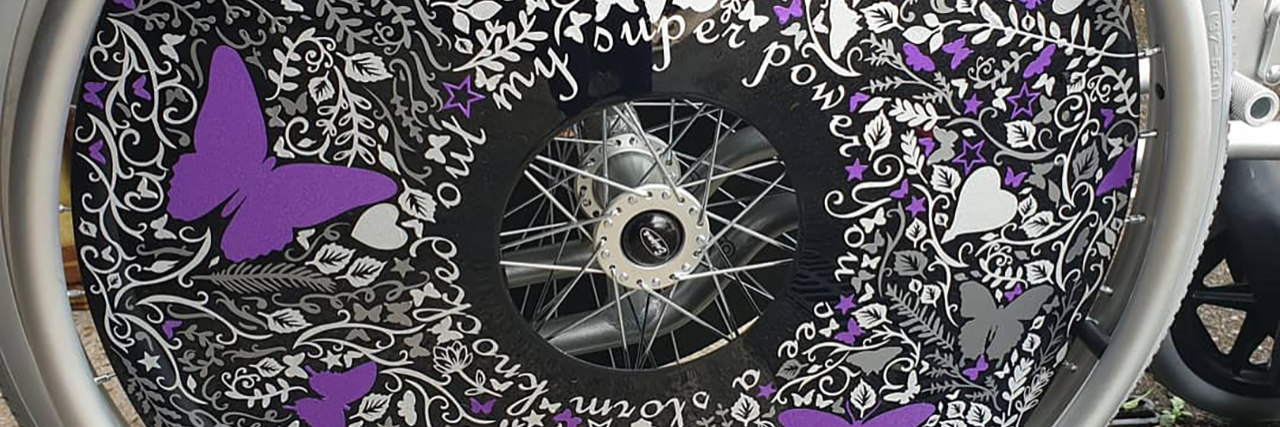 Elaine's wheelchair spoke guard decorated with butterflies and vines made of purple and white cricut vinyl.