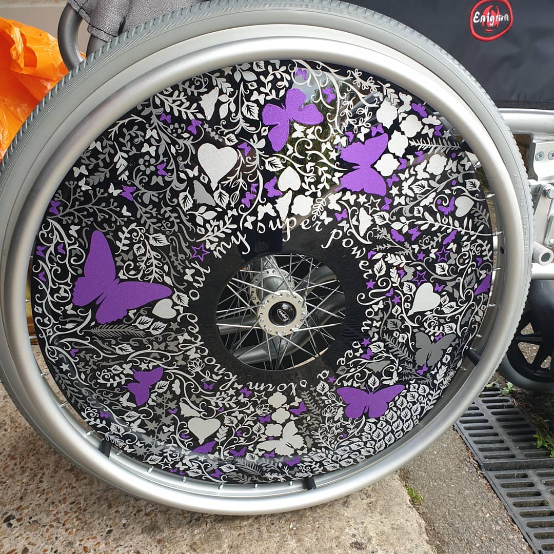 Elaine's wheelchair spoke guard decorated with butterflies and vines made of purple and white cricut vinyl.