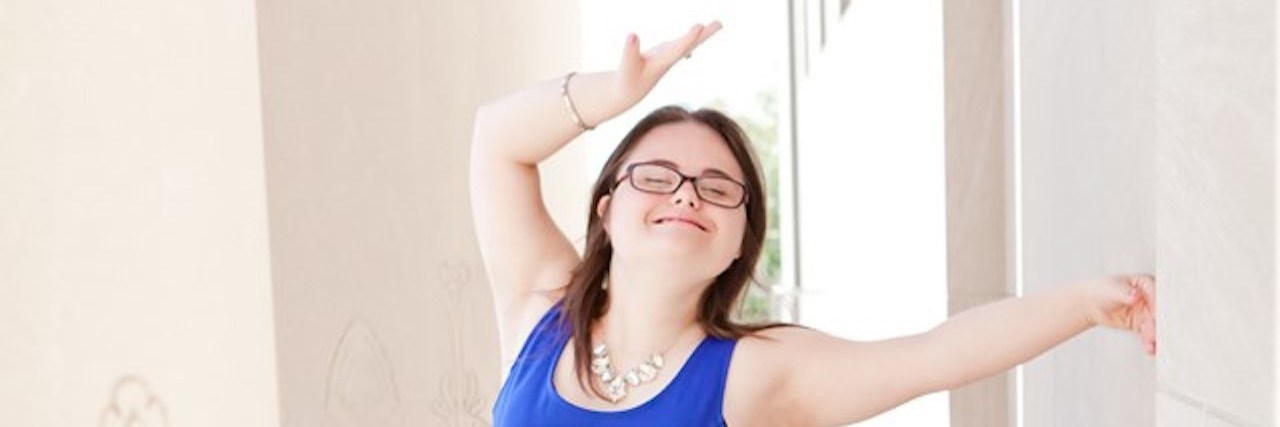 Young woman with Down syndrome posing for camera wearing bright blue dress