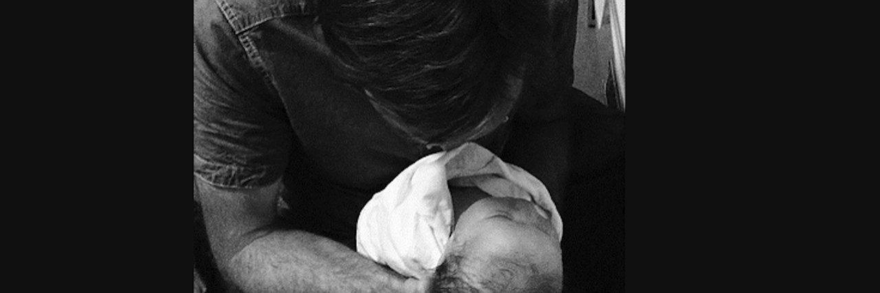 The Pink Hallway of the Hospital Where My Baby Was Treated man holding newborn on lap