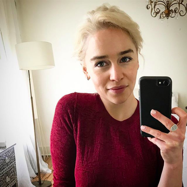 Emilia Clarke wearing a red sweater and taking a selfie in the mirror