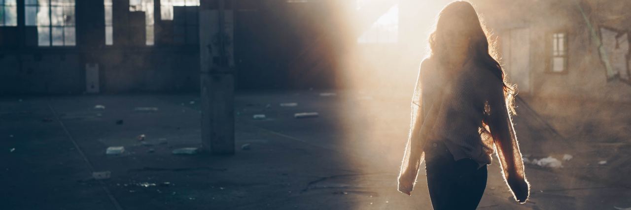 Feeling Chronic Emptiness With Borderline Personality Disorder photo of woman walking in empty warehouse silhouetted by sunlight