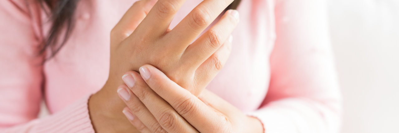 8 Rheumatoid Arthritis Triggers You're Not the Only One Experiencing White woman with brown hair touches painful, arthritic hand.