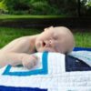 Baby with Down syndrome sleeping outdoors on blanket