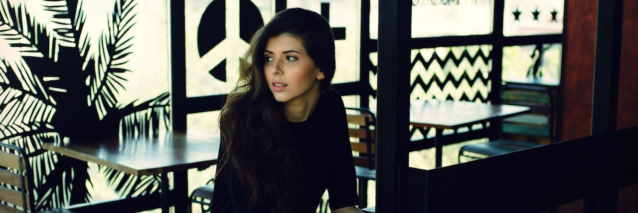 What a Good Day Is Like When You Have a Mental Illness A woman sitting in a cafe, looking behind her.