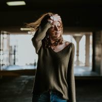 photo of woman standing in dark building with hand in hair