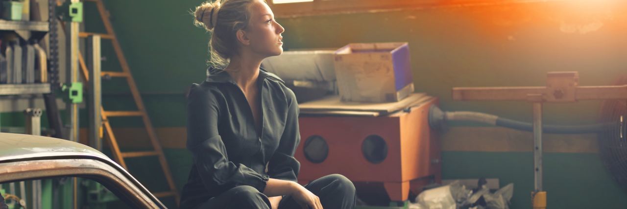 My Journey as a Teen Survivor of Abuse and Suicide photo of young woman sitting in garage on old car looking toward sunlight through window