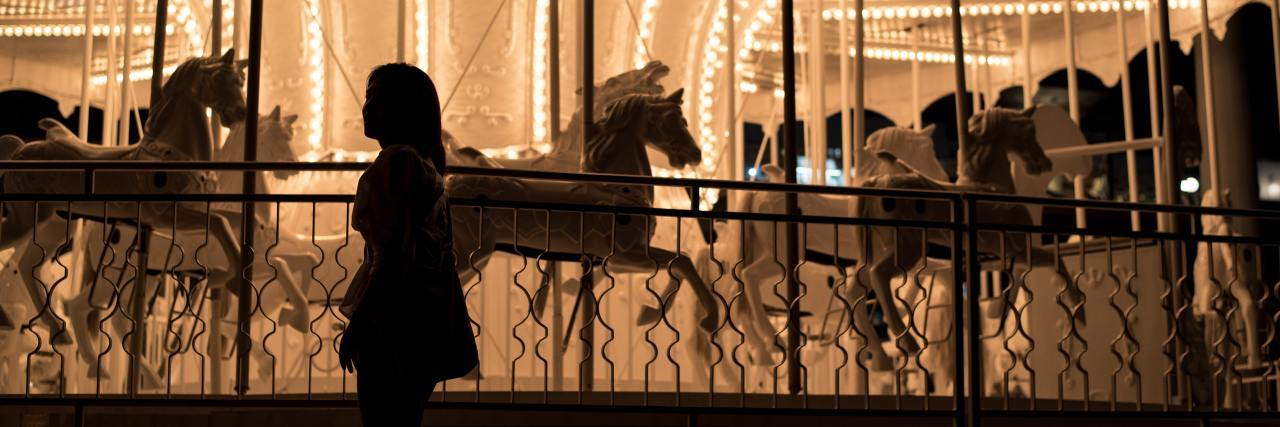 girl standing next to carousel