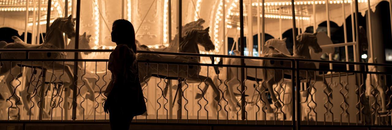 How Anxiety and ADHD Make My Mind Feel Like a Carousel girl standing next to carousel