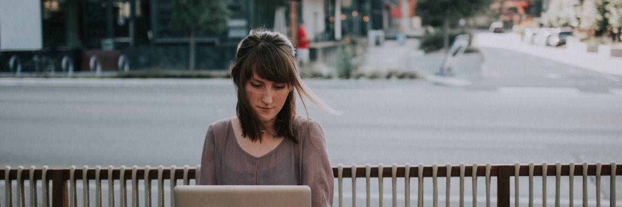 A woman on her lap top sitting outside at a cafe